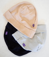 A stack of three Leblok baby beanie hats in beige, black, and light grey colors, made from EMF protective fabric